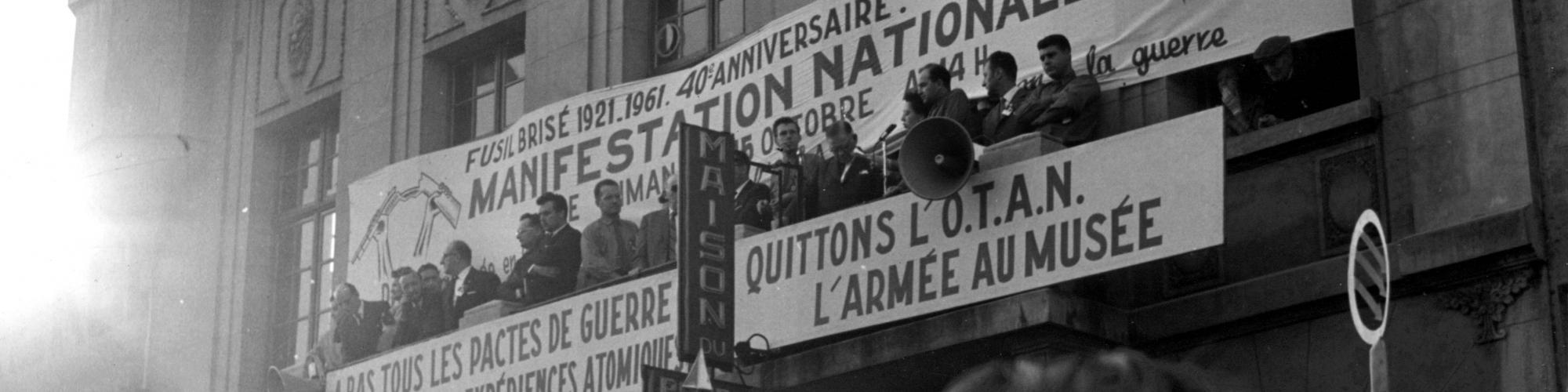 Manifestatie van het gebroken geweer. La Louvière, 15.10.1961. Op de tribune : Stéphane Huvenne, Léon Hurez, Ernest Glinne, Jean Van Lierde, Georges Dobbeleer, Daisy Lenaerts, Hector Roland, Claude Thiry en Joseph Schoofs. Foto nr 125471, Fonds Jean Van Lierde, copyrights CegeSoma/Rijksarchief.